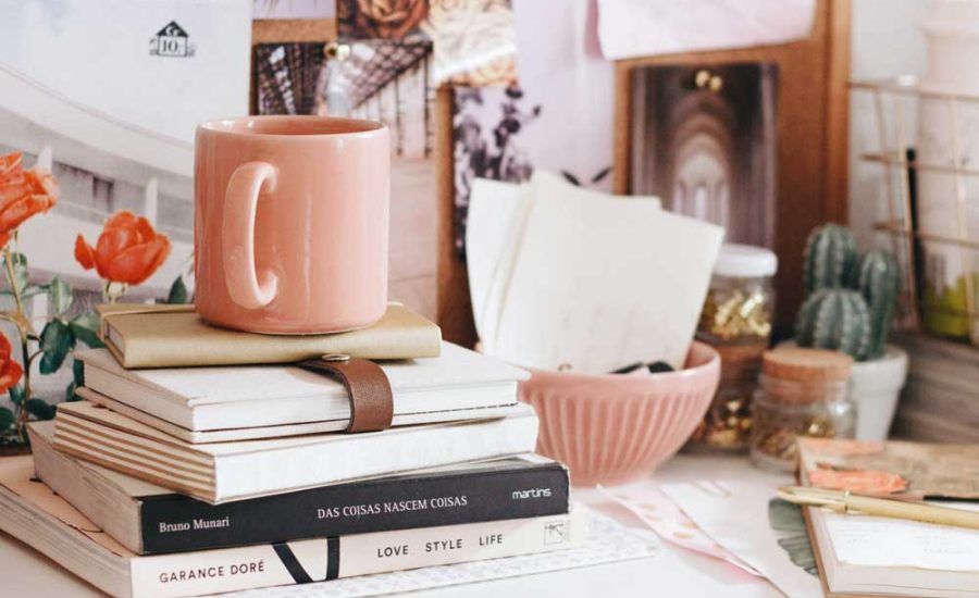 tasse à café en céramique rose sur un tas de livre